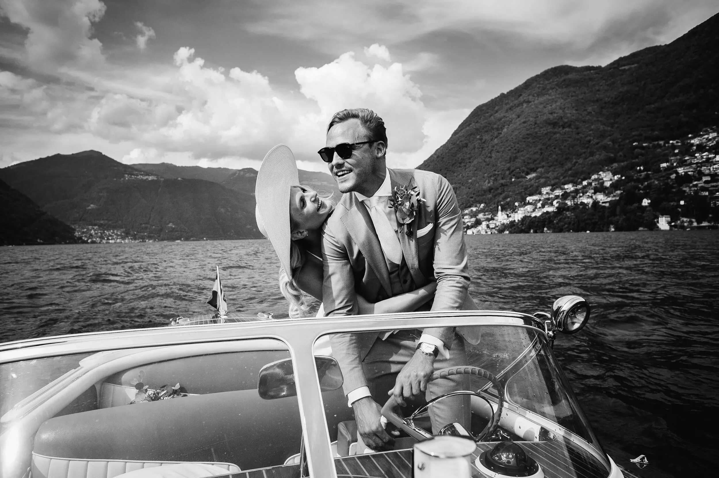 Bride with hat playfully grabs groom against a red wall in Lake Como, Italy