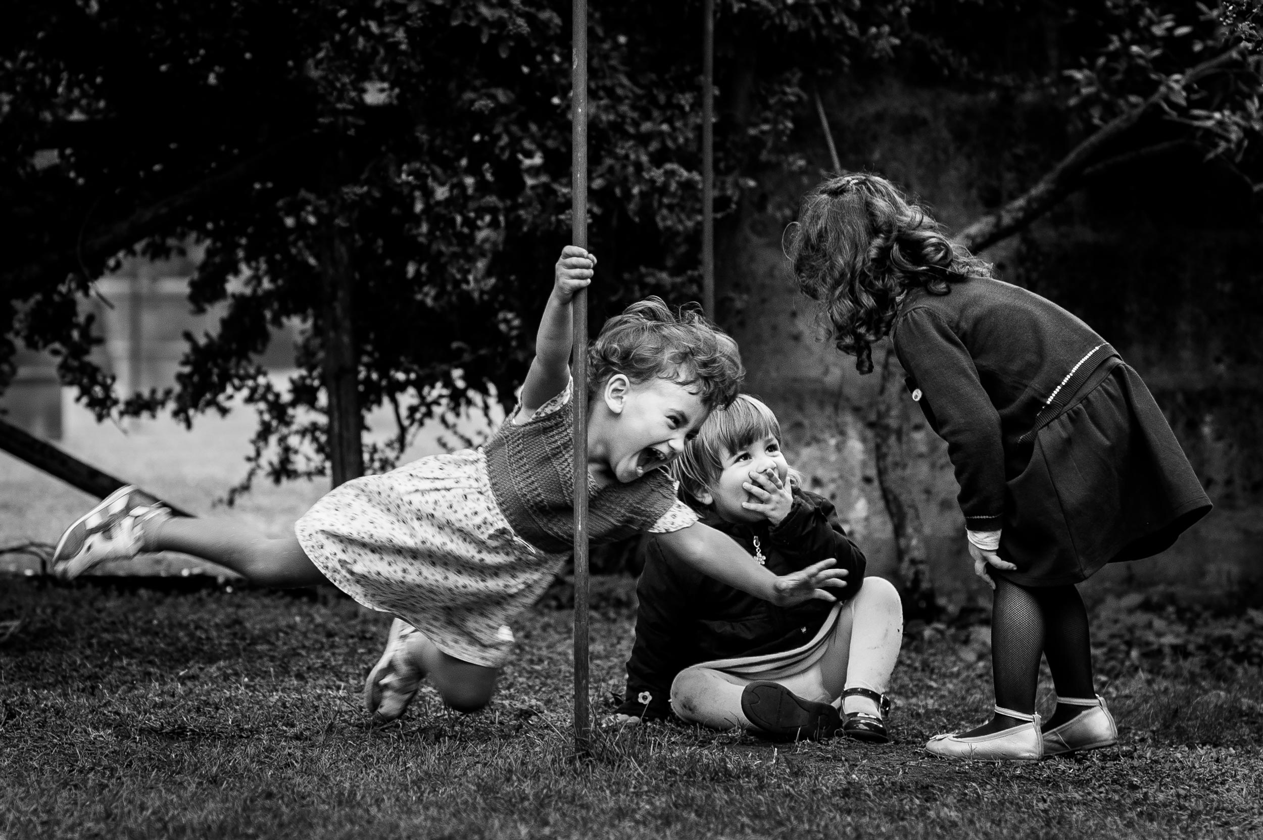 girl playing with a pole among children black and white wedding photography