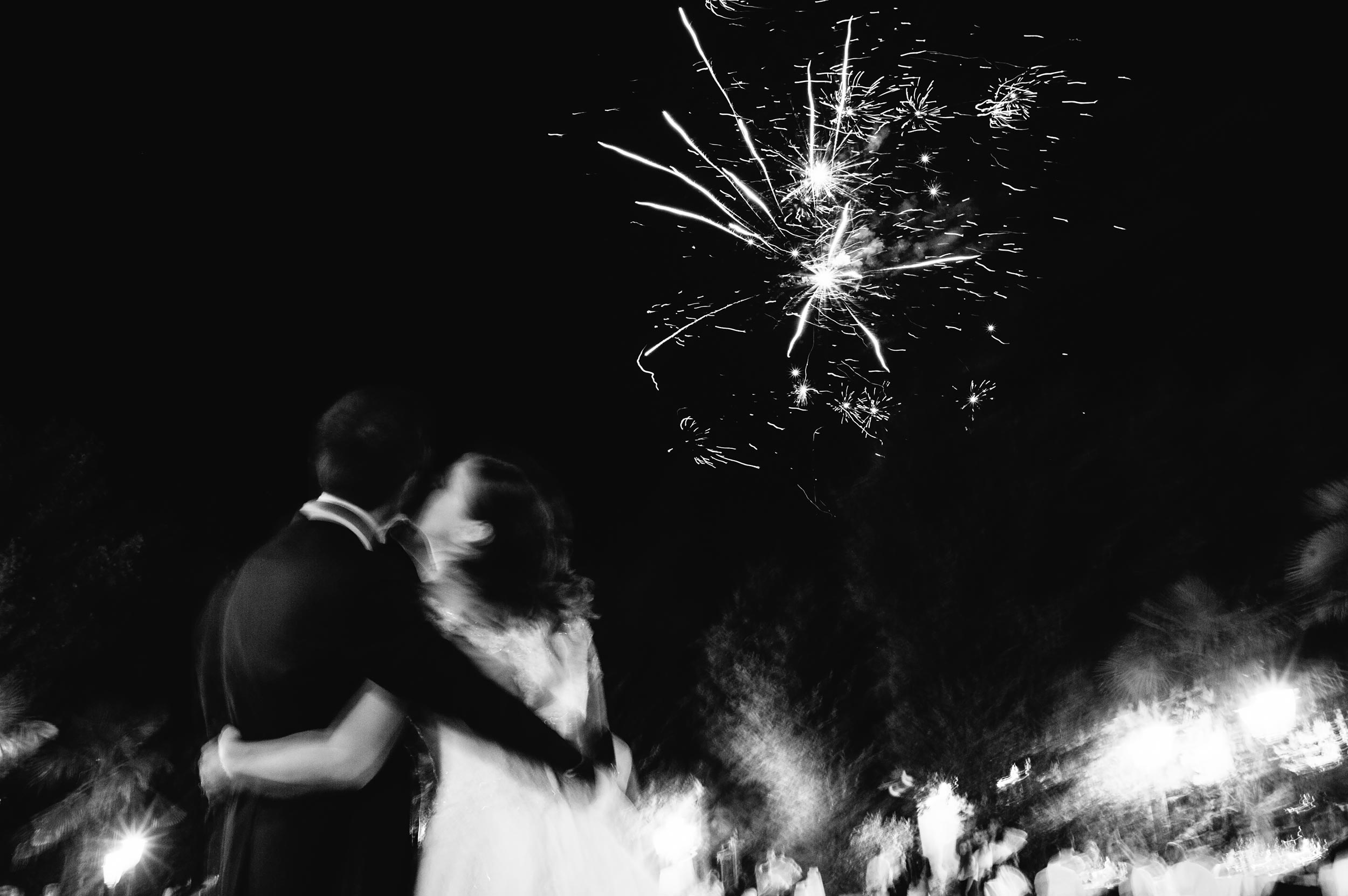 the bride kisses the groom under fireworks black and white wedding photography