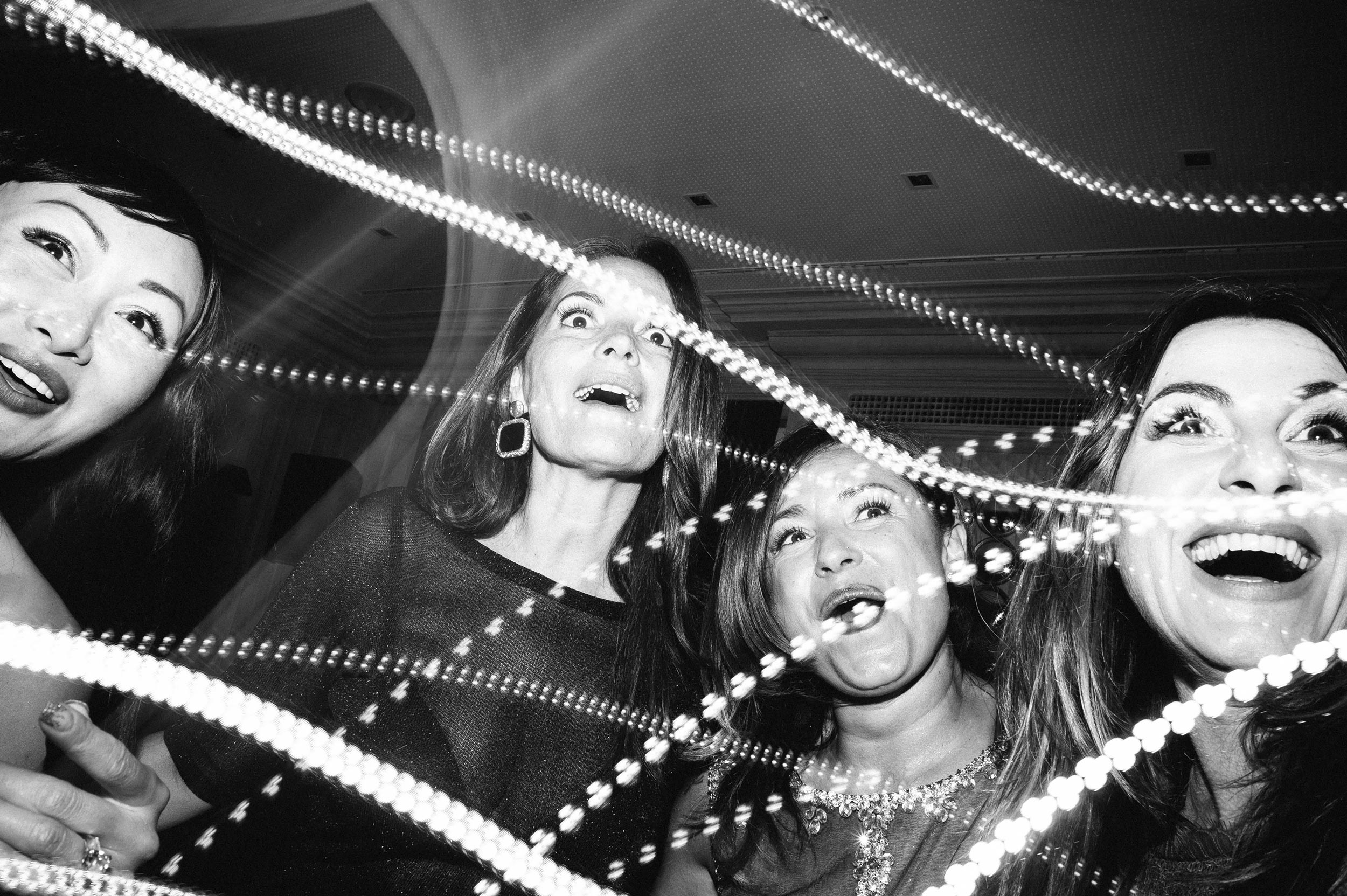 astonished women among lights during wedding reception black and white wedding photography