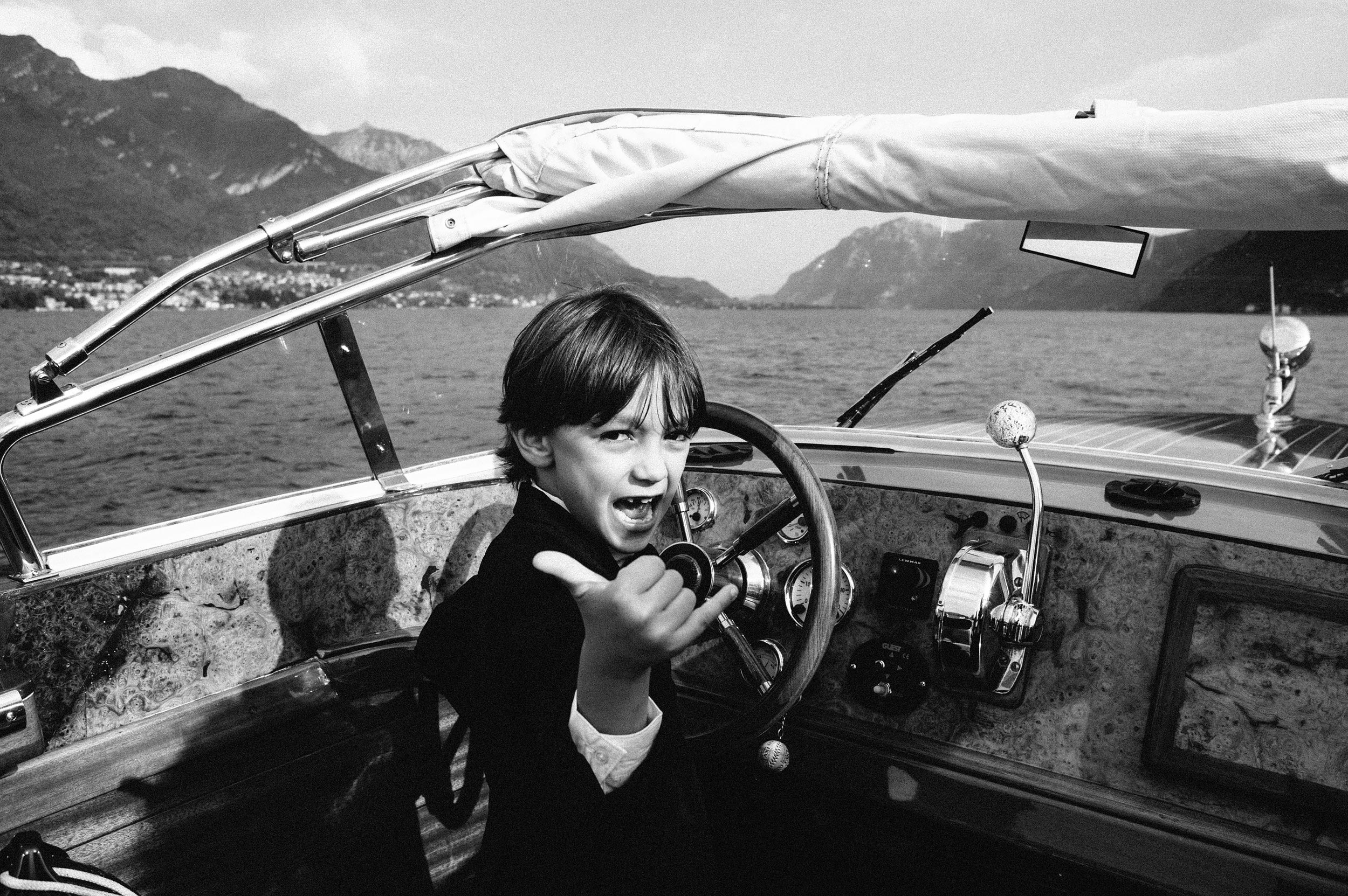 kid driving a motorboat on lake como black and white wedding photography