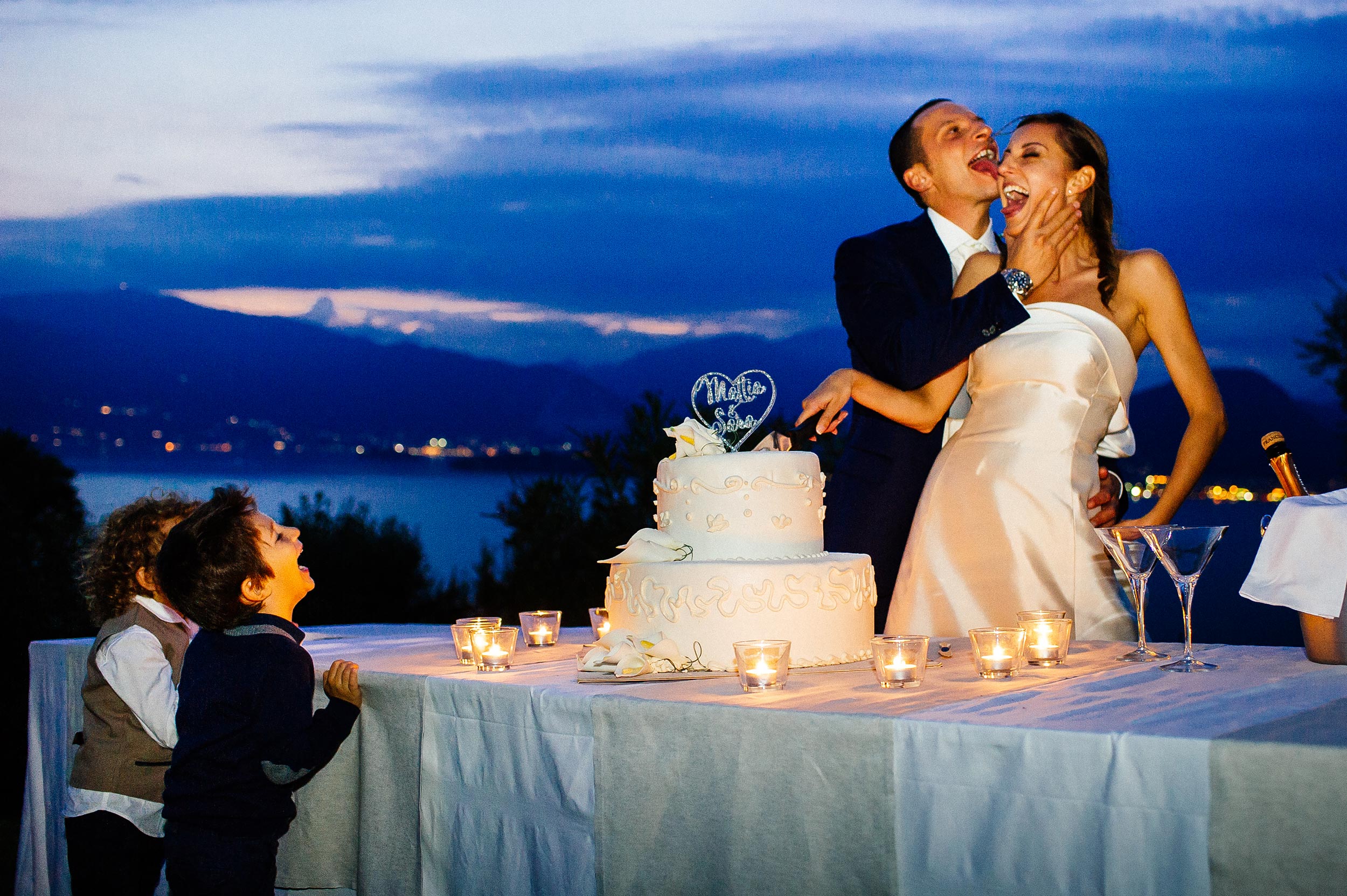kids laugh at groom licking brides face during cake cutting colors