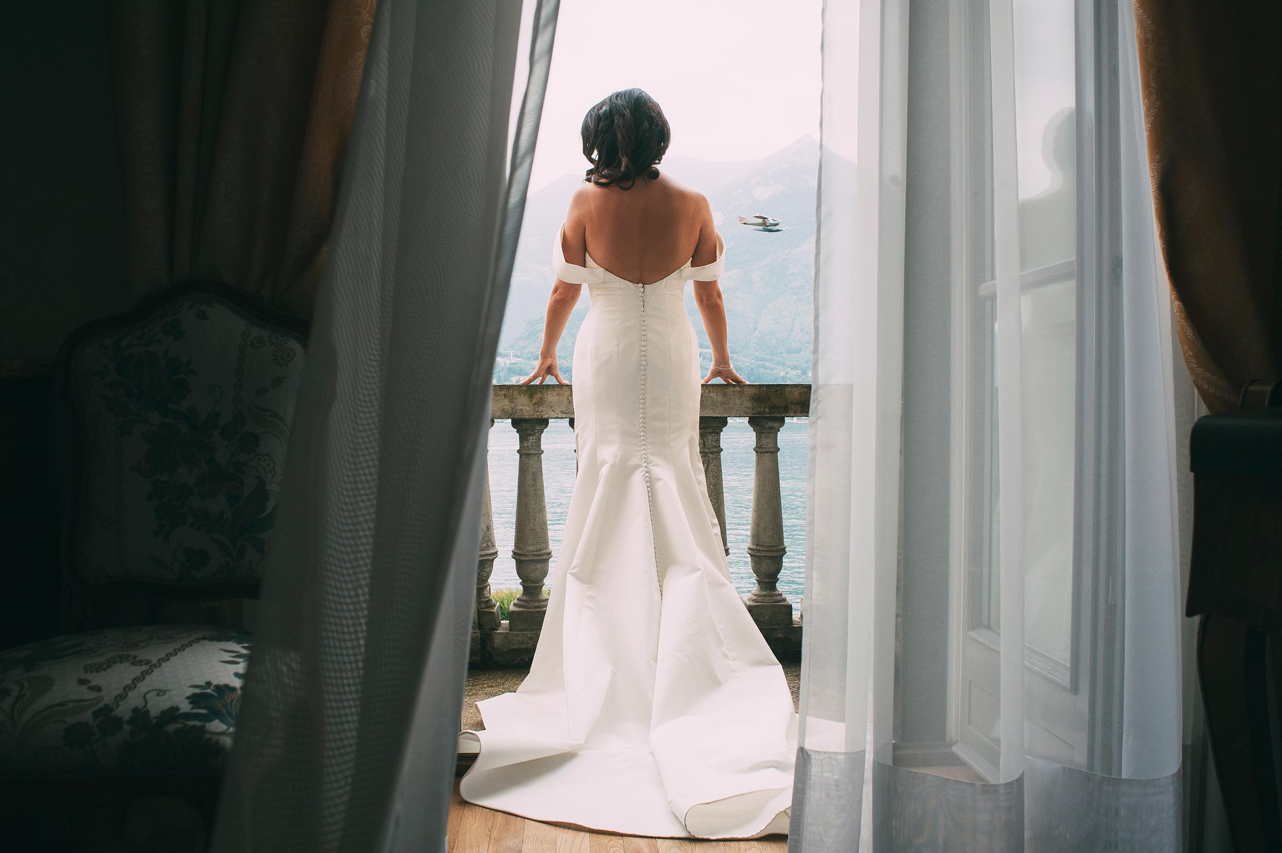 lake como bride on the balcony while airplane passes by wedding italy