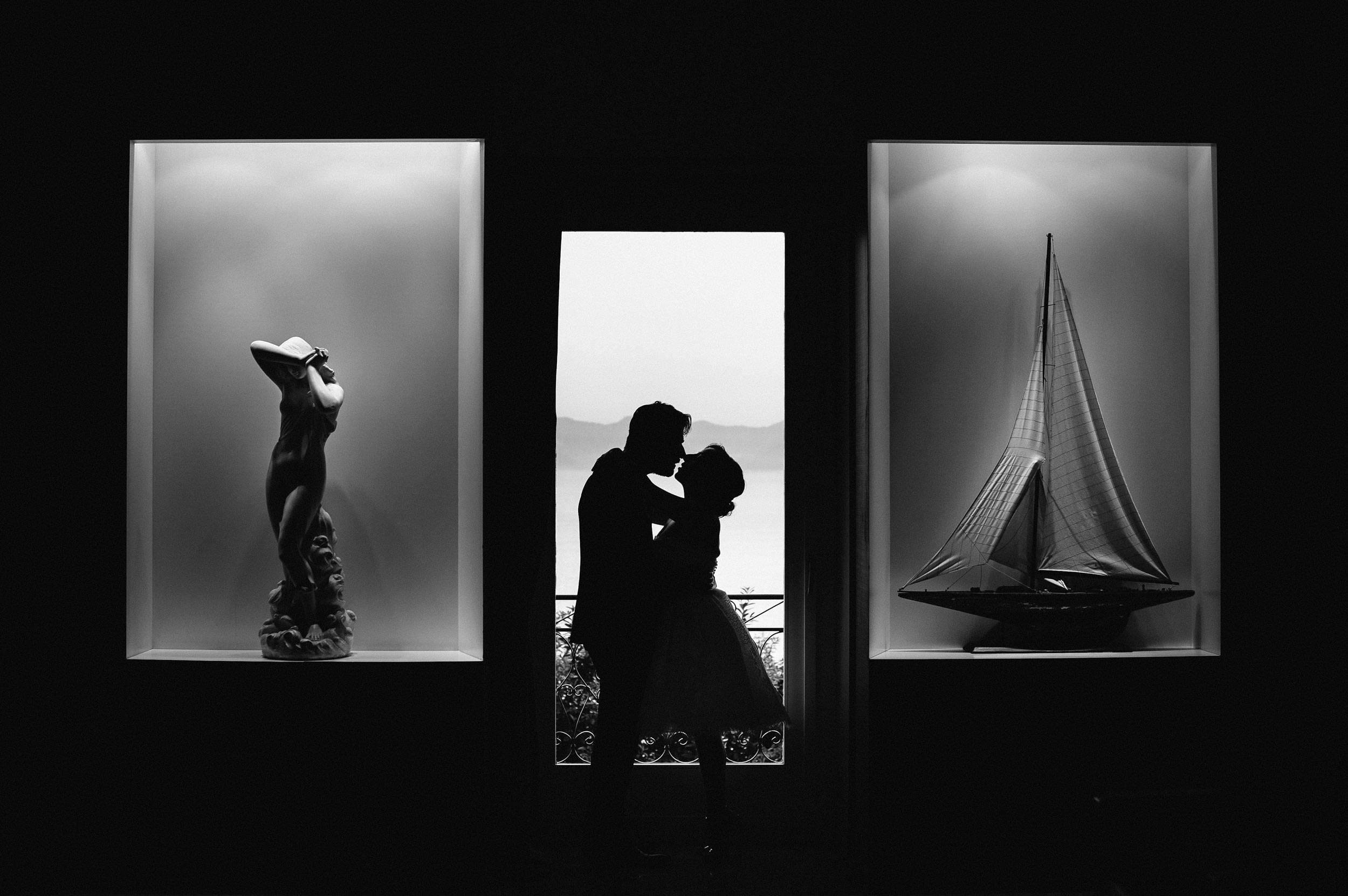 bride and groom portrait with statue and sailboat window above the sea Alessandro Avenali